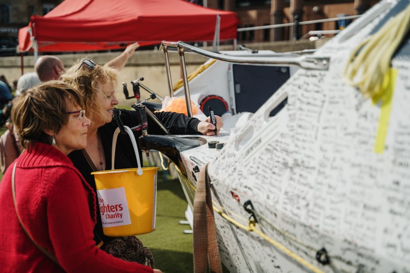 Two ladies signing a boat for charity